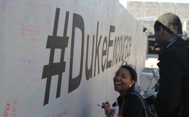 A student writes a supportive phrase on the barrier surrounding the Bryan Center Plaza expansion construction. The Duke Honor Council sponsored the project as part of its campus-wide #DukeEncourage campaign.